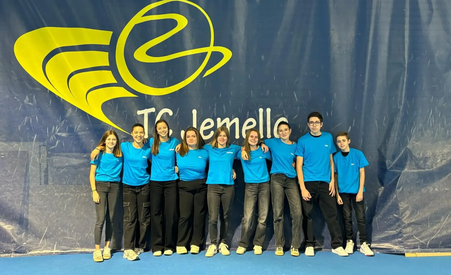Équipe du Tennis Club de Jemelle devant le logo du club